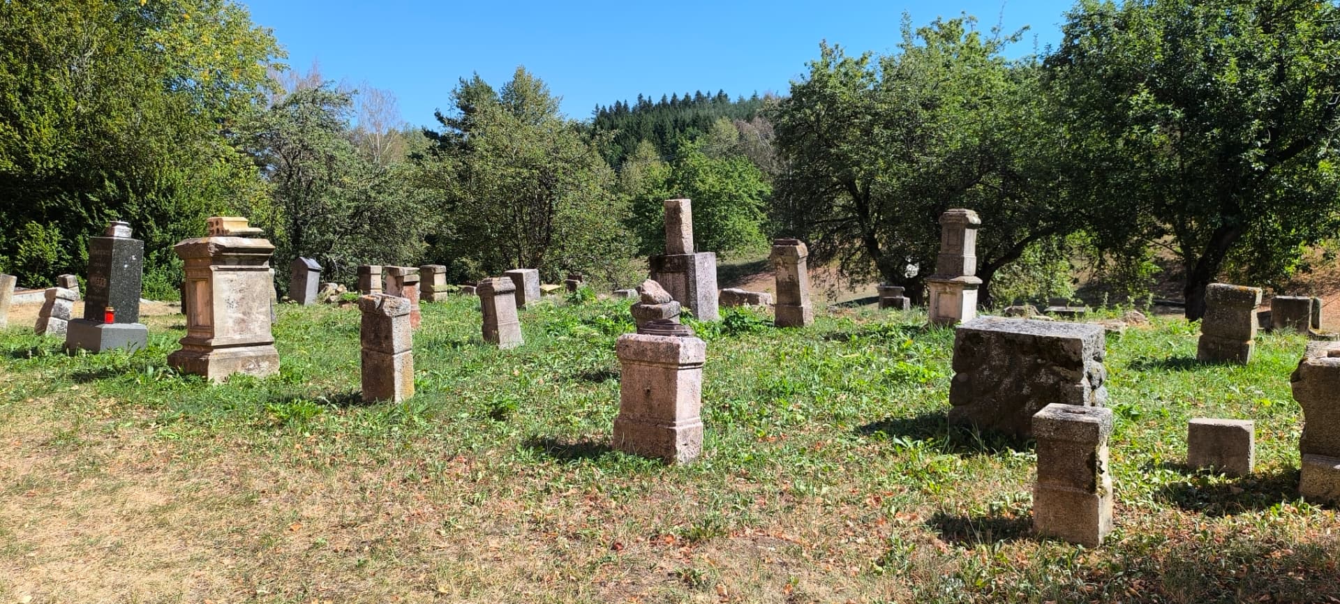 Hřbitov u kostela sv. Mikuláše s řadami kamenných náhrobků v trávě