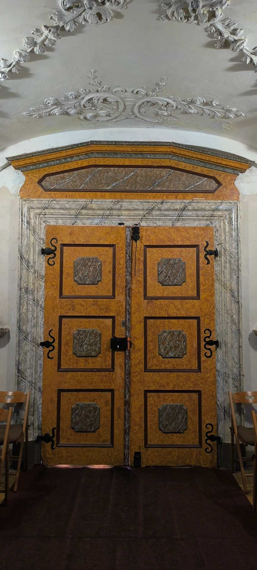 Malované dřevěné dveře s kovovými panty v interiéru kostela