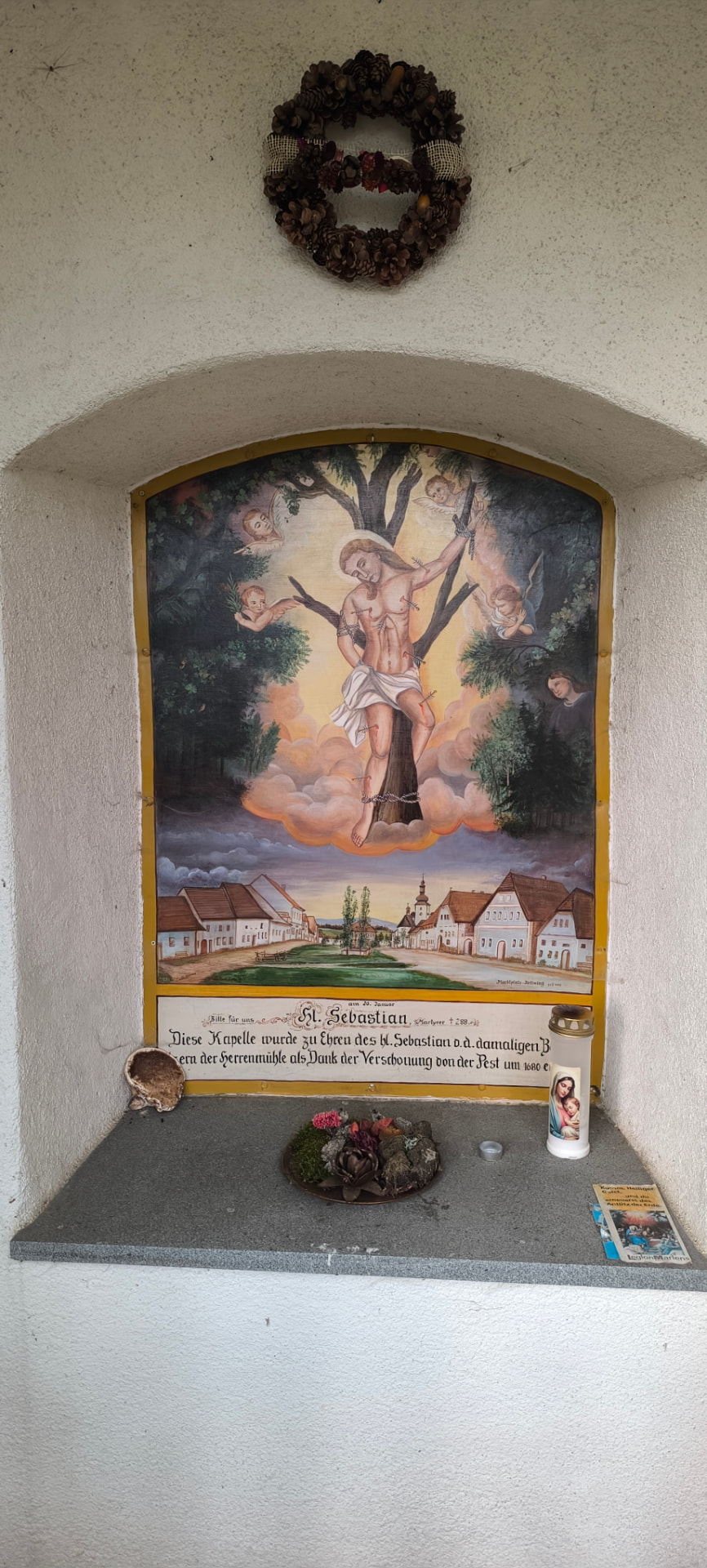 Obraz svatého Šebestiána ve výklenku kapličky, pod ním namalované náměstí Cetvin.