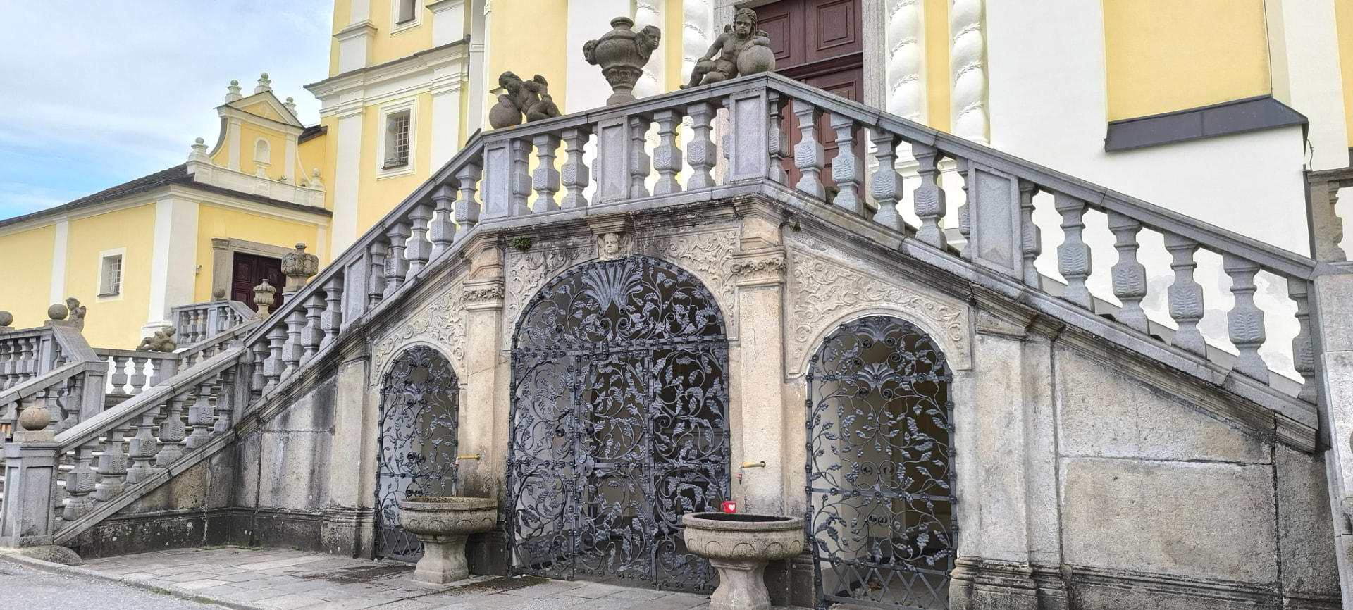 Dvouramenné schodiště ke kostelu na Dobré Vodě s kovanými mřížemi a kohoutky s vodou z pramene