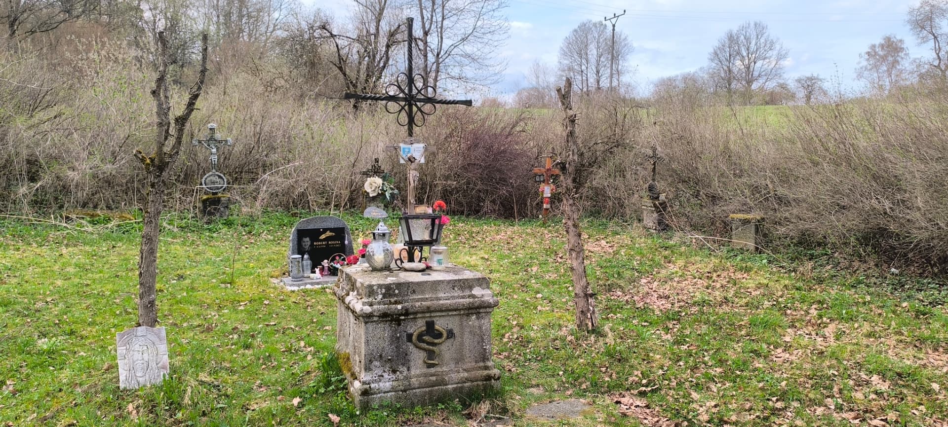 Kovaný kříž a kamenný náhrobek na cetvinském hřbitůvku.